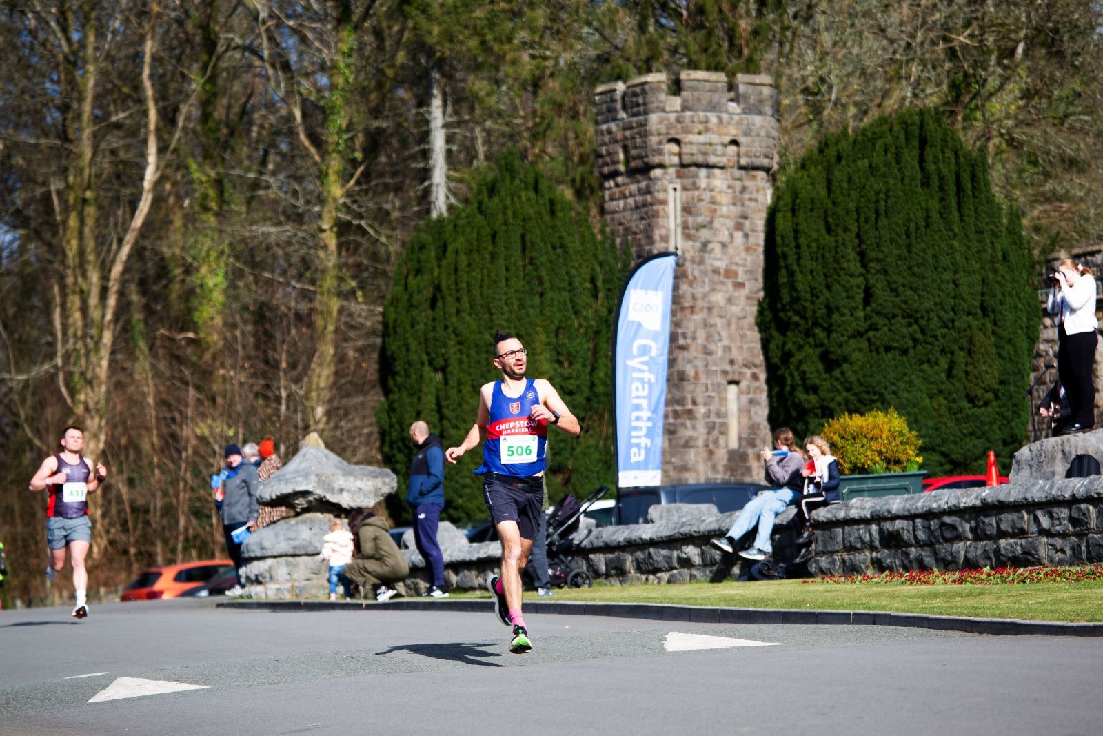 A runner in a blue and red jersey running in front of a blue flag and castle turret..jpg